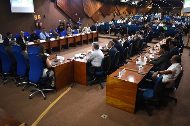 Foto mostra pessoas num evento realizado em um auditório lotado