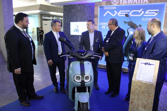 Foto mostra um grupo de homens conferindo exposição de uma motocicleta sustentável