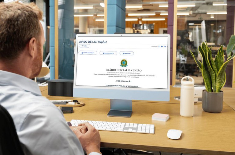 Homem sentado à frente de uma tela de computador com aviso de um edital de licitação