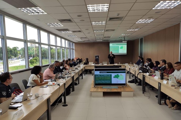 Sala com diversas pessoas reunidas para participando da palestra. Palestrante ao centro conduzindo as atividades.