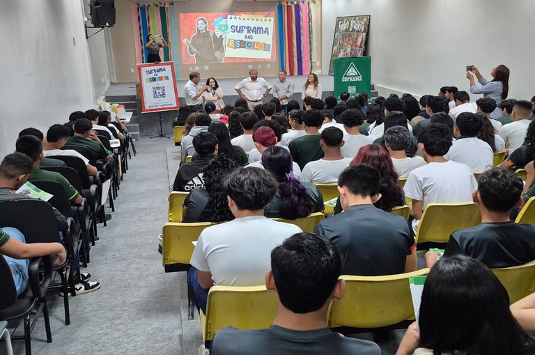 Grupo de alunos em uma sala de aula com pessoas de pé a frente deles