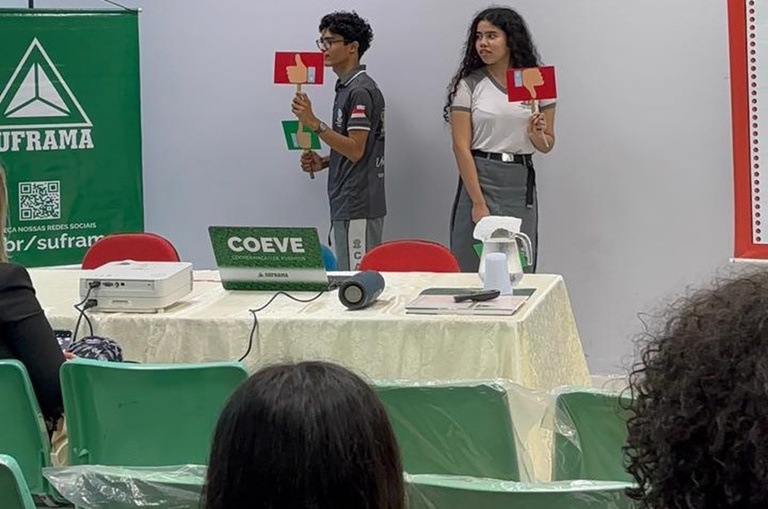 Foto mostra dois estudantes segurando placas durante uma dinâmica escolar