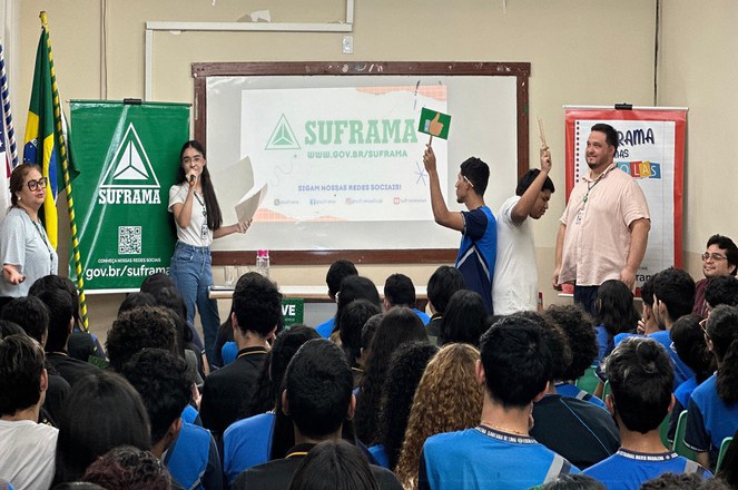 Foto mostra dois jovens segurando umas placas, enquanto uma jovem falava ao microfone