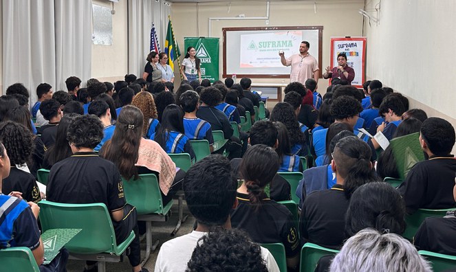 Foto mostra homem segurando um copo, enquanto outro homem fala ao microfone