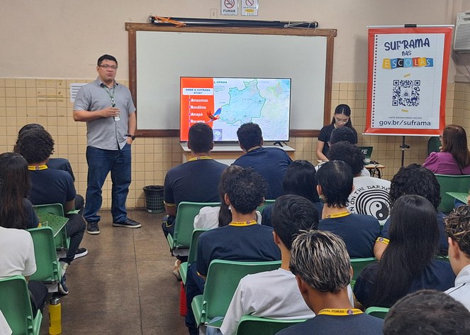 Foto mostra homem de blusa cinza falando a um grupo de estudantes