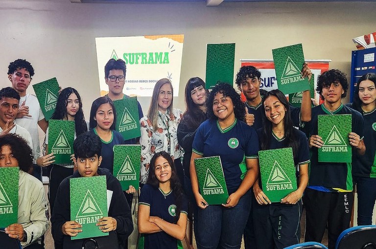 Foto mostra grupo de pessoas segurando pastas verdes nas mãos