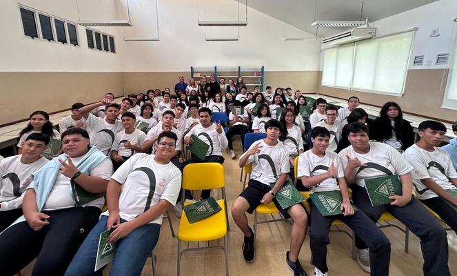 Foto mostra grupo de estudantes reunidos, após palestra e com os organizadores da ação ao fundo