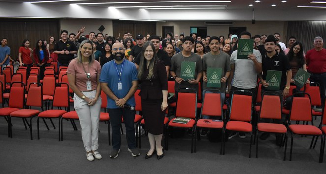 Foto mostra grupo de pessoas posando para sessão de fotografia dentro de um auditório