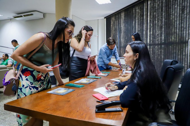 Foto mostra mulheres prestando atendimento e sendo atendidas com informações sobre determinado evento