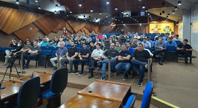 Foto mostra várias pessoas sentadas em um auditório