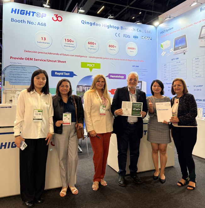 Foto mostra homem de óculos e cartilha nas mãos, posando ao lado de um grupo de mulheres