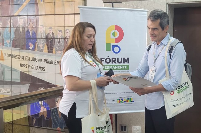 Foto mostra homem mostrando publicação a uma mulher