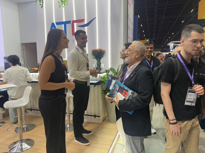 Foto mostra homem de blazer conversando com mulher de preto em um evento público