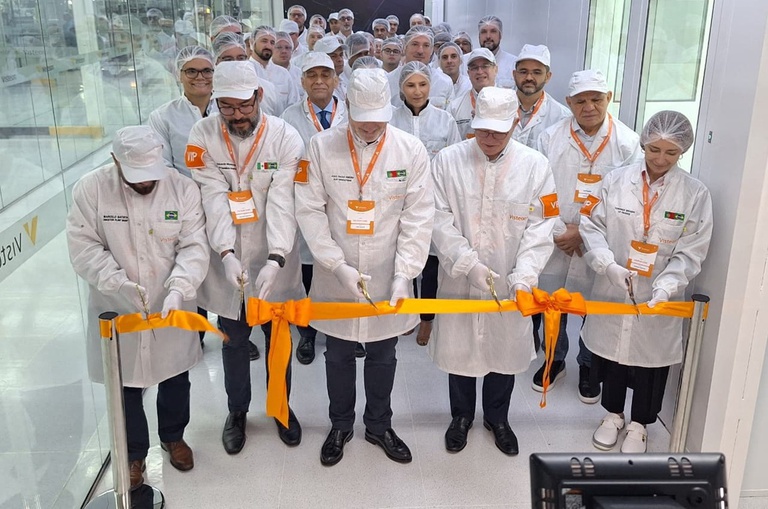 Foto mostra pessoas com jaleco e touca brancos descerrando uma faixa