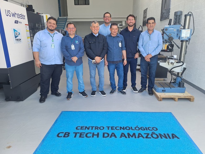 Foto mostra grupo de pessoas posando paraz fotografia em frente a um tapete azul