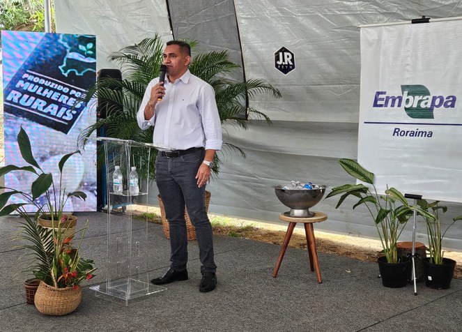 Foto mostra homem de camisa branca e microfone na mão falando em púbico