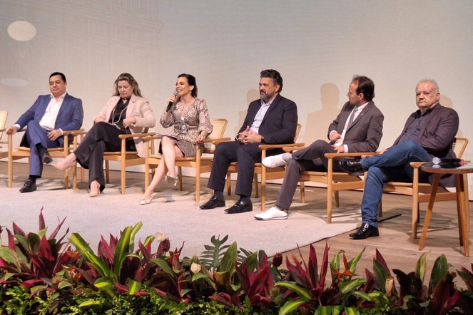 Foto mostra mulher de vestido falando ao microfone