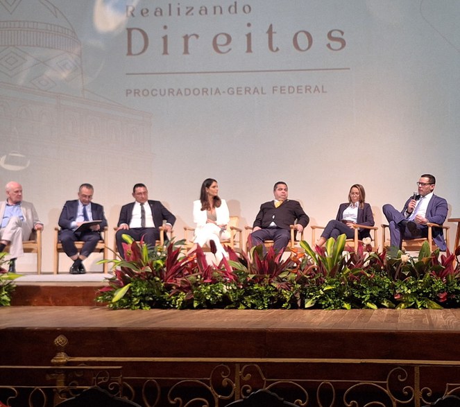 Foto mostra homem de paletó azul falando ao microfone