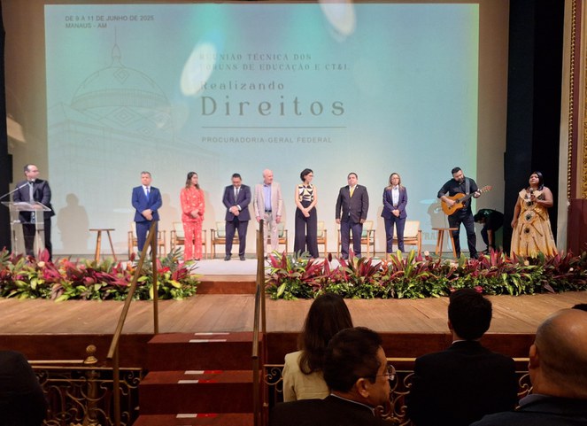 Foto mostra um rapaz tocando violão e uma mulher cantando no palco