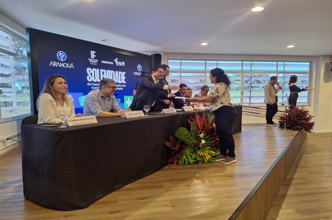 Foto mostra homem entregando certificado a uma mulher