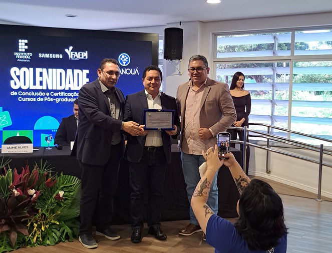 Foto mostra homem recebendo placa