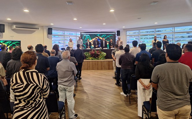 Foto mostra pessoas em pé num evento