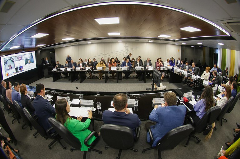 Foto mostra pessoas em numa mesa grande 