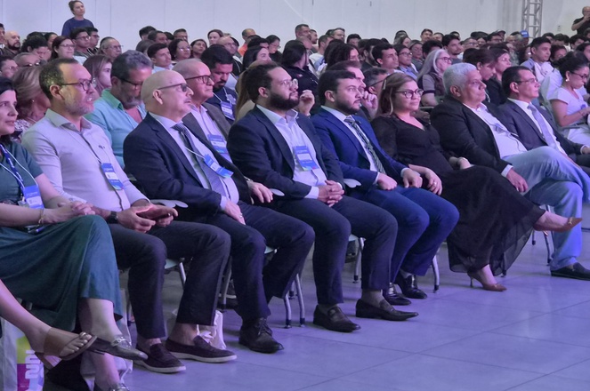 Foto mostra pessoas sentadas num auditório lotado