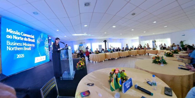 Foto mostra mulher falando ao microfone em evento público