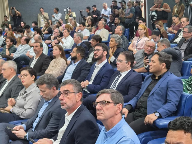 Foto mostra pessoas sentadas num auditório lotado
