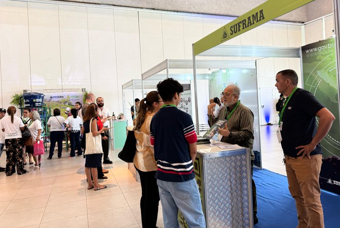 Foto mostra homem de blusa marron falando com uma mulheres e um adolescente, observado por outro homem de blusa preta
