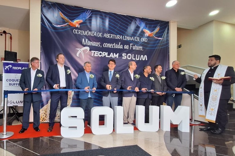 Foto mostra padre rezando e homens se preparando para fazer uma inauguração