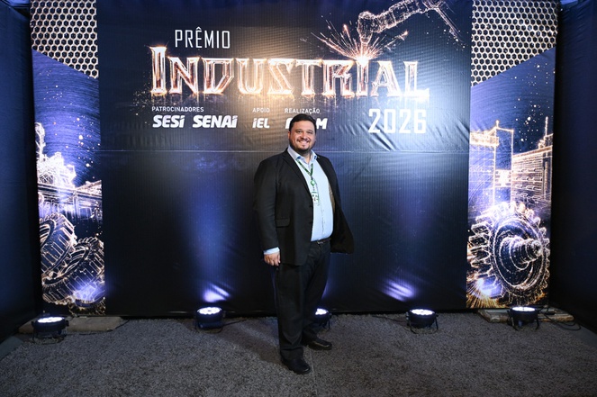 Foto mostra homem em pé, com painel ao fundo