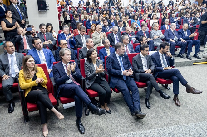 Foto mostra pessoas sentadas em um auditório lotado