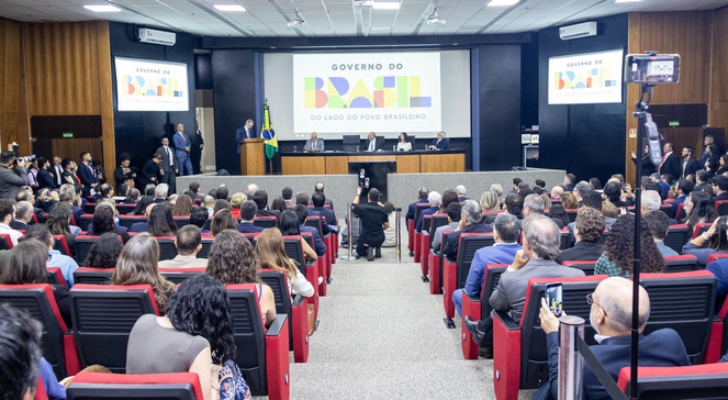 Foto mostra pessoas sentadas num auditório lotado