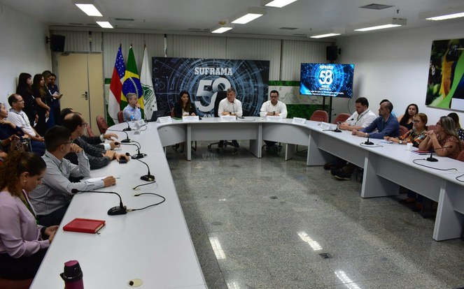 Foto mostra grupo de pessoas reunidas numa sala fechada