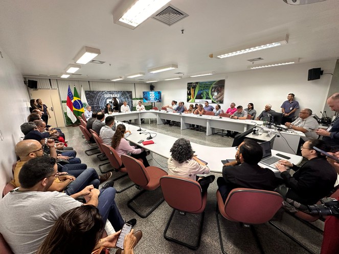 Foto mostra um grupo de pessoas reunidas em evento fechado