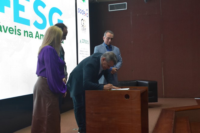 Foto mostra homem assinando um documento