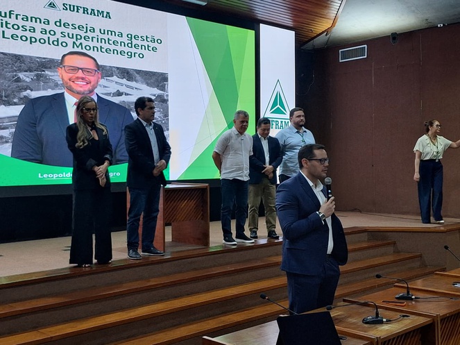 Foto mostra homem de blazer azul falando ao microfone