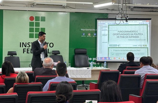 Foto mostra homem de blazer ministrando uma palestra com um telão como apoio