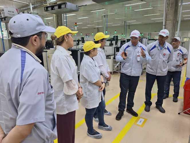 Fotos mostra pessoas de bata e chapeu ouvindo uma explicação de um homem