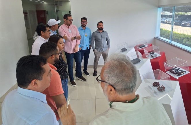 Foto mostra pessoas olhando para uma vitrine com equipamentos eletrônicos