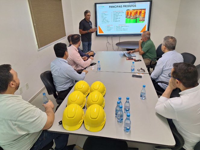 Foto mostra pessoas numa reunião com telão como apoio