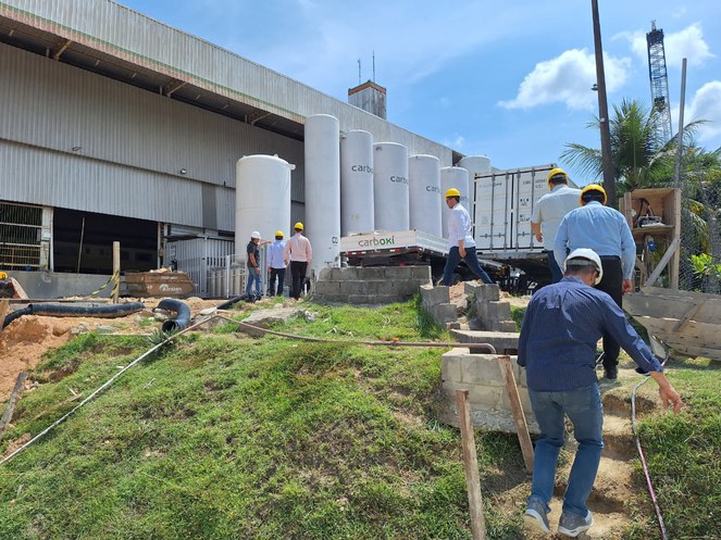 Foto mostra fábrica e pessoas caminhando nela