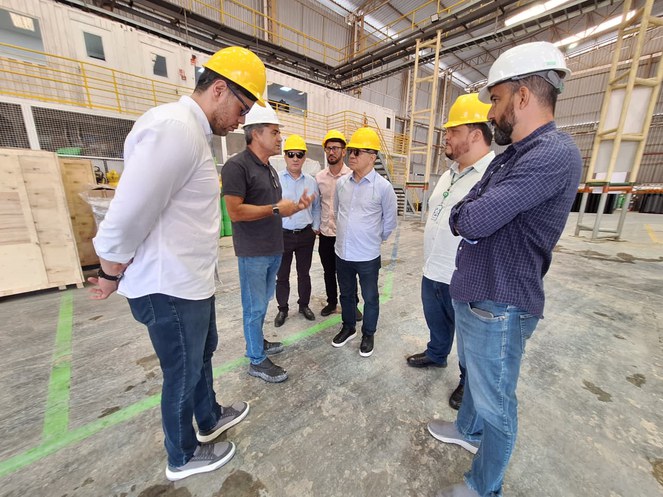 Foto mostra pessoas conversando com capacete na cabeça