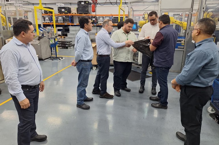 Foto mostra homens olhando para um material plástico preto