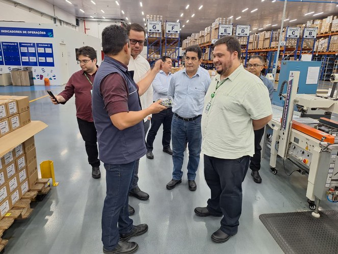 Foto mostra homem segurança uma peça e outros olhando