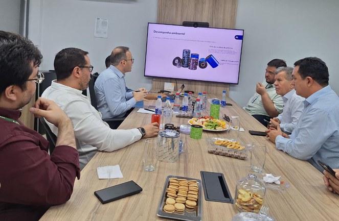 Foto mostra homens em uma reunião, com um telão como apoio