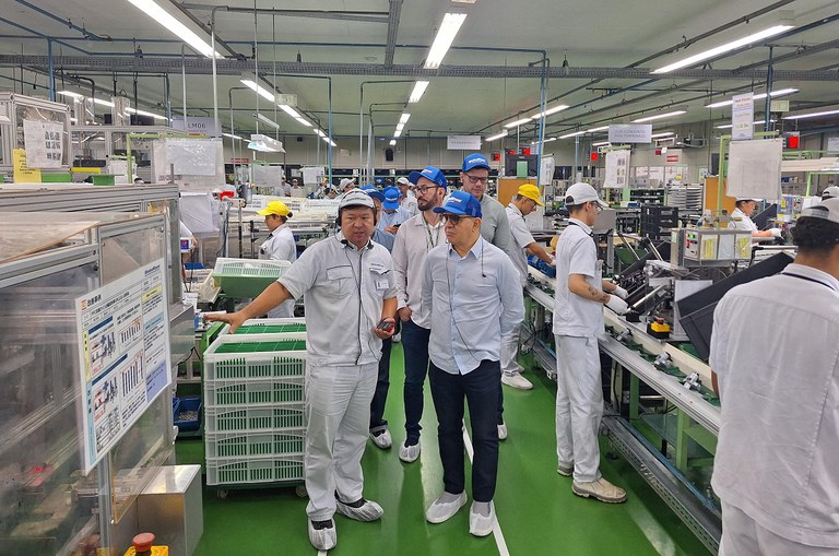 Foto mostra um grupo de pessoas em visita a uma empresa