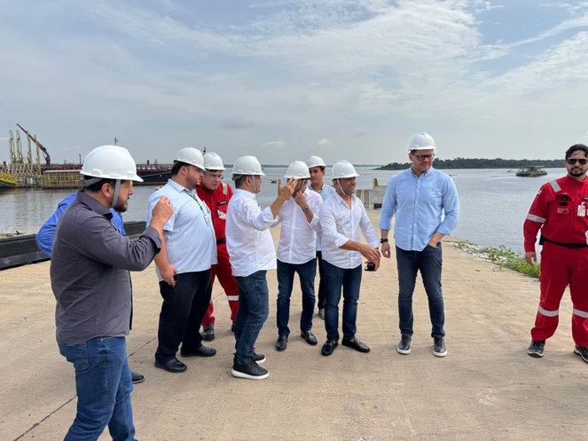 Foto mostra grupo de homens conversando às margens de um rio